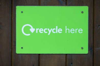 a green recycle here sign on a wooden wall